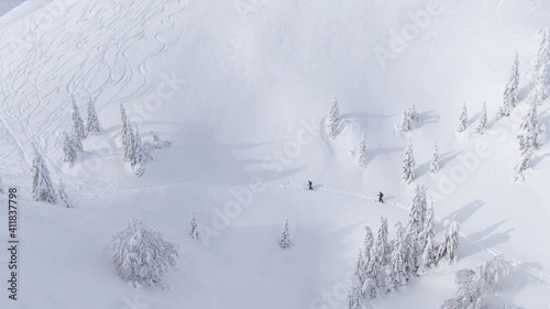 DRONE: Tourists on splitboarding trip trek along a slope covered in powder snow. photo