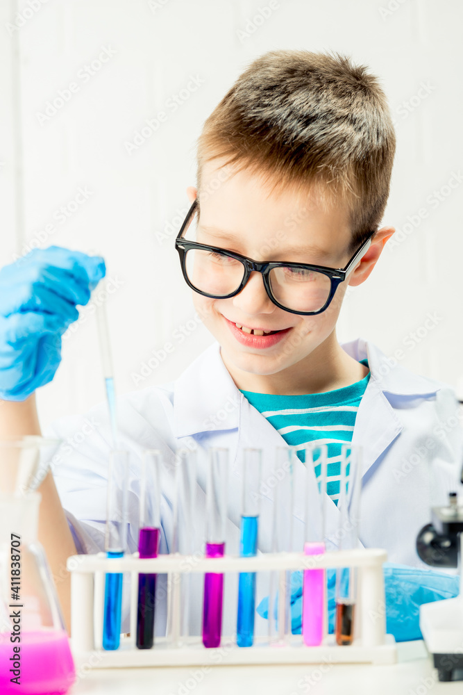A schoolboy studies multi-colored substances in test tubes, conducts experiments - a portrait on a white background. Concept for the study of coronavirus in the laboratory A schoolboy studies multi-colored substances in test tubes, conducts experiments - a portrait on a white background. Concept for the study of coronavirus in the laboratory