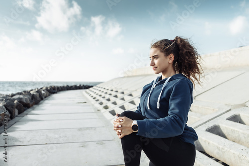 Curly sports woman in sportswear doing body warming up before training on urban beach. Healthy lifestyle © splitov27