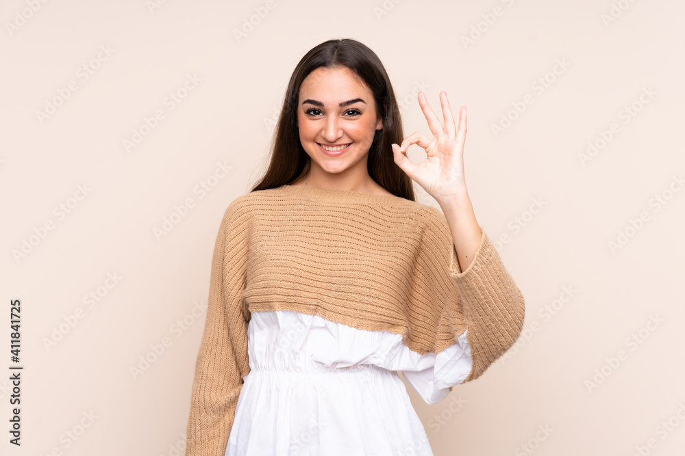Young caucasian woman isolated on beige background showing ok sign with fingers
