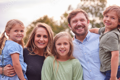 Portrait Of Smiling Family In Summer Garden With Parents Holding Son And Daughter In Arms © Monkey Business