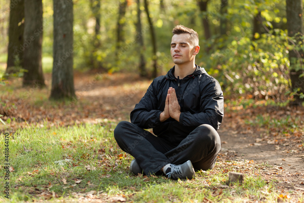 Sport man meditates in the lotus position in the autumn forest. Sport man meditates in the lotus position in the autumn forest.
