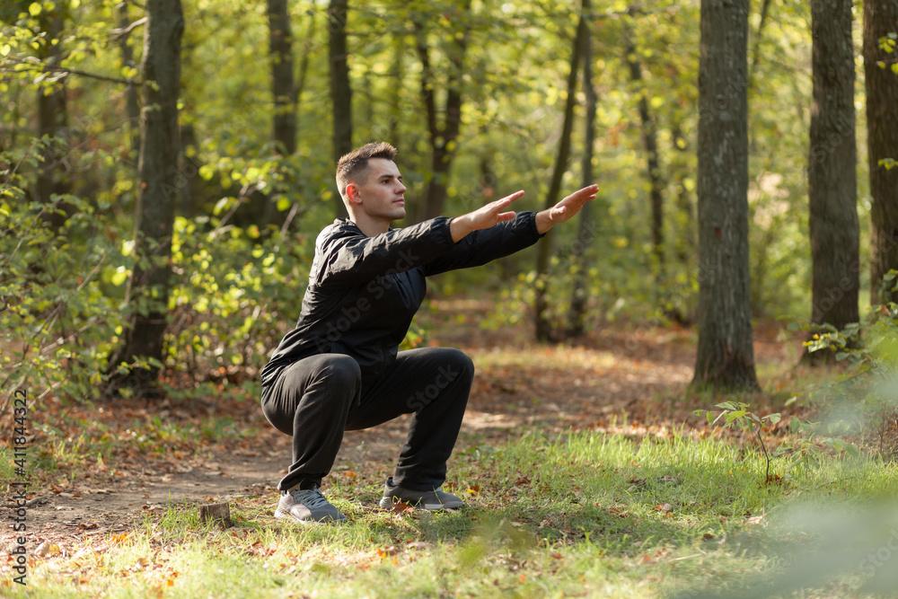 Active sport man trains warm-up exercises in the autumn forest. Healthy lifestyle. Outdoor workout Active sport man trains warm-up exercises in the autumn forest. Healthy lifestyle. Outdoor workout