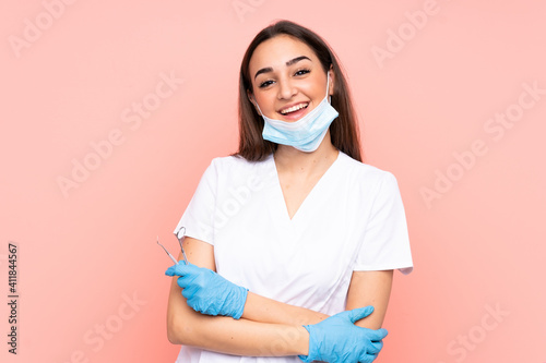 Woman dentist holding tools isolated on pink background laughing