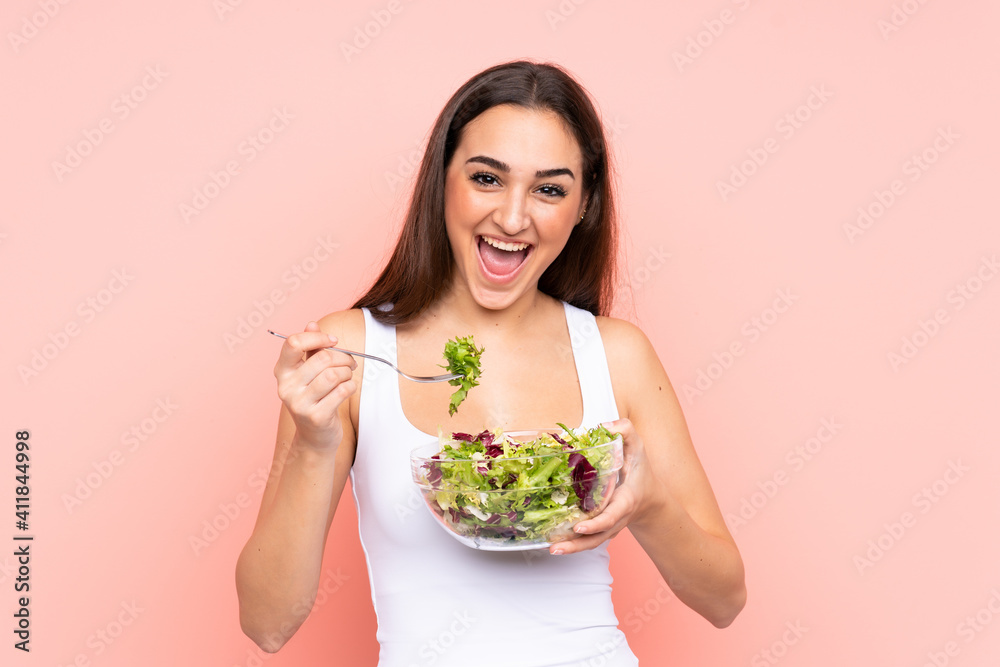 Young caucasian woman holding a salad isolated on pink background Young caucasian woman holding a salad isolated on pink background