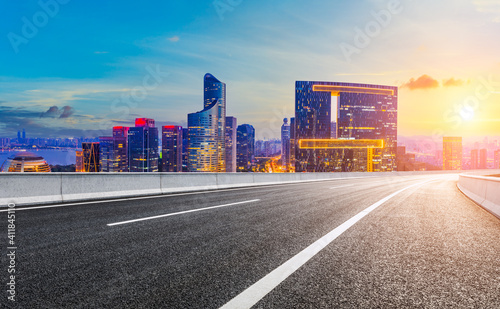 Asphalt road and modern city skyline with buildings in Hangzhou at sunset.