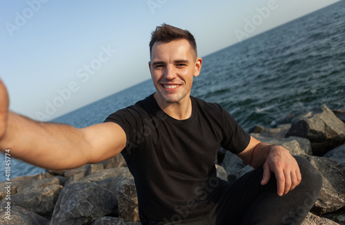 Selfie portrait of handsome man on the coast with stones