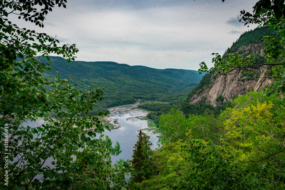 Huge cliffs flowing down into the bay and bushes in Fjords du Saguenay, Quebec Province, Canada, from Notre-Dame-du-Saguenay track during a cloudy day