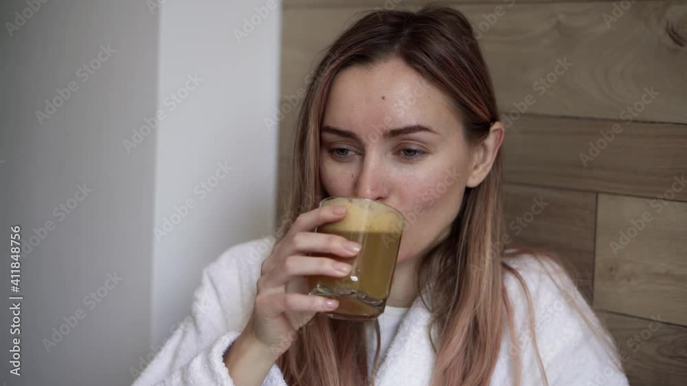 Young woman drinking fresh apple juice in kitchen in the morning Young woman drinking fresh apple juice in kitchen in the morning