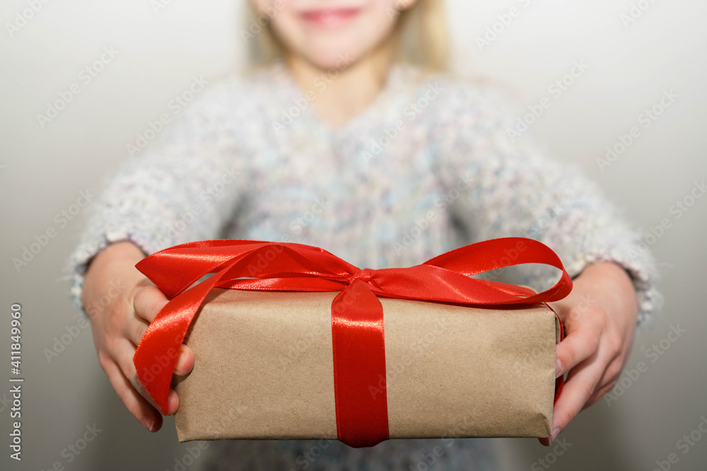 Happy girl holding a gift with a red ribbon Happy girl holding a gift with a red ribbon