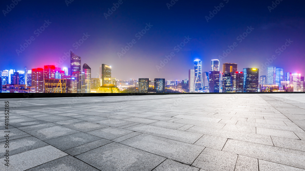 Empty square floor and modern city skyline with buildings in Hangzhou at night.