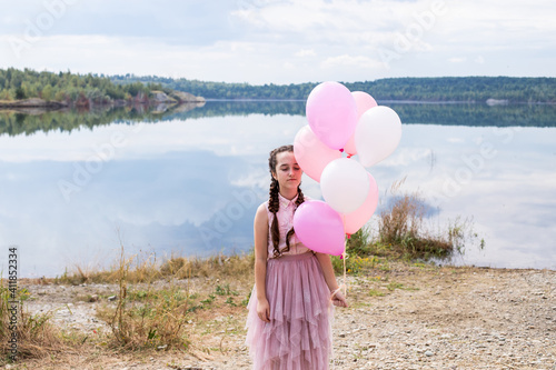 girl on the lake in a pink dress and with inflatable balloons, emotions