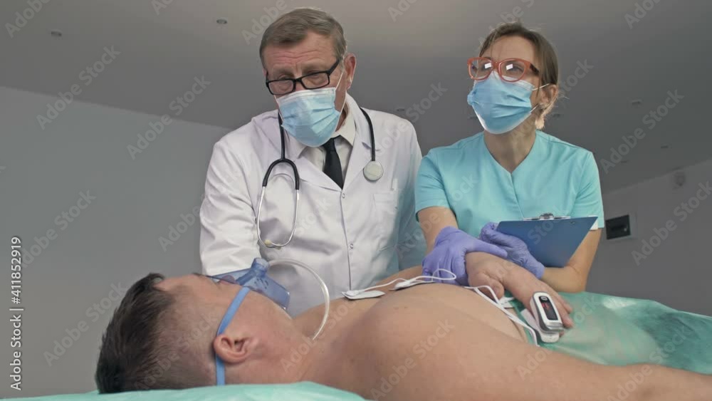 Doctors examining a patient on bed in the emergency room of the hospital. Doctors examining a patient on bed in the emergency room of the hospital.