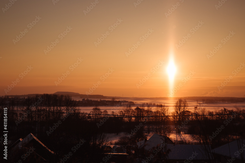 A rare atmospheric phenomenon is the solar light pillar. Beautiful morning winter landscape. Open space and fields at dawn. Good weather. Anomaly. Orange sun and sky. Environment and nature. Horizon