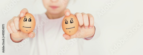 Young girl show two eggs with sad face isolated on white background. Easter and social distance concept. photo