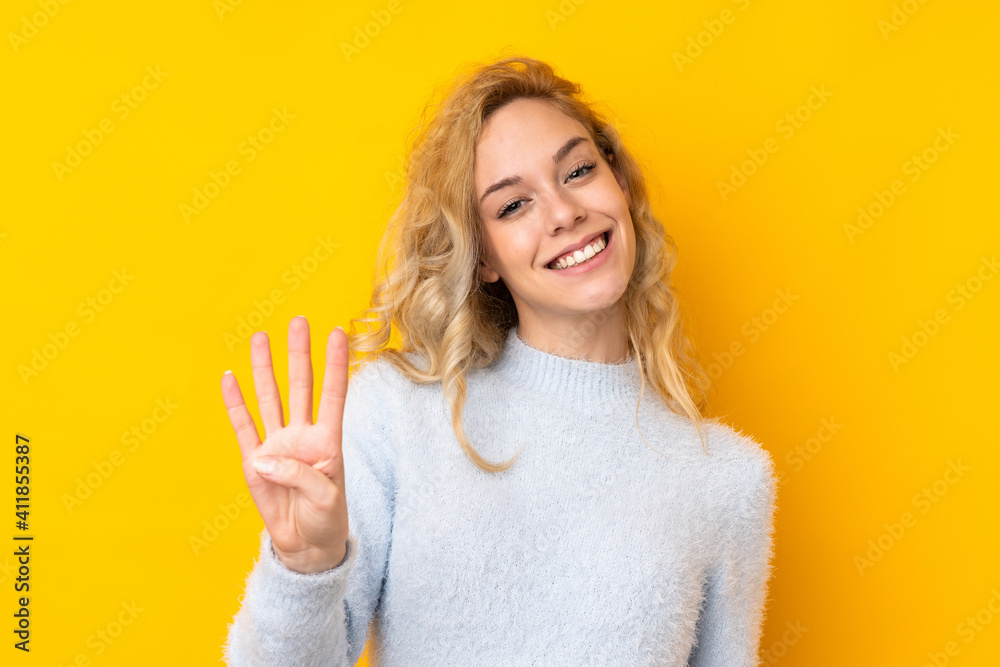 Young blonde woman isolated on yellow background happy and counting four with fingers - obrazy, fototapety, plakaty 
