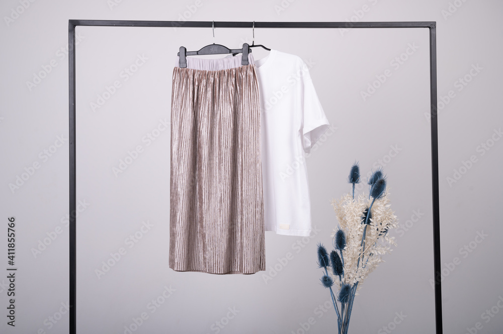 Capsule spring wardrobe concept. T-shirt and skirt in pastel colors handing on a rack.