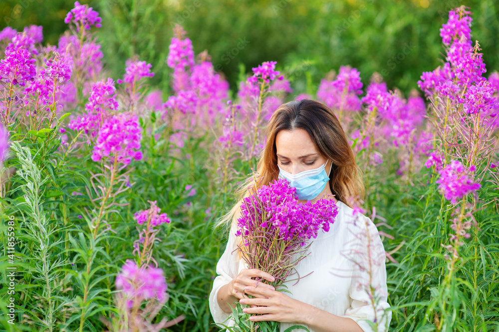 A girl in a medical mask sniffs a bouquet of purple flowers in her hands. Spring aggravation of allergies concept. Security measures during the coronavirus pandemic A girl in a medical mask sniffs a bouquet of purple flowers in her hands. Spring aggravation of allergies concept. Security measures during the coronavirus pandemic