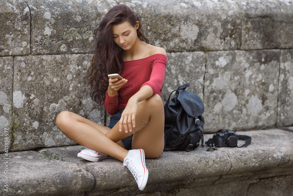 Woman with a Backpack, Phone, and Camera on the City Street