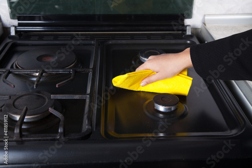Woman cleans the kitchen gas with a cloth.
