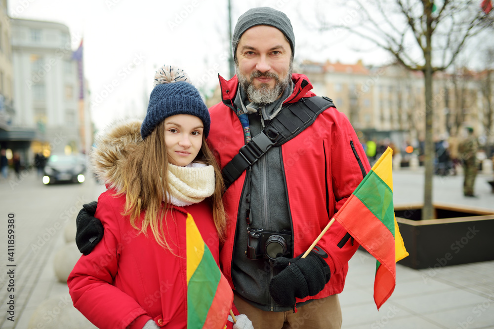 Father and daughter holding Lithuanian flag on Lithuanian Independence Day in Vilnius. Happy family celebrating national holiday.