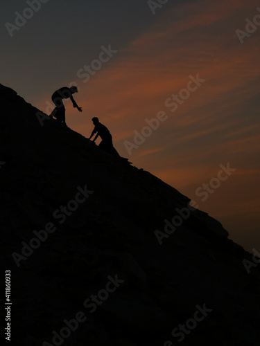 a man helping another man to climb © leo morgen