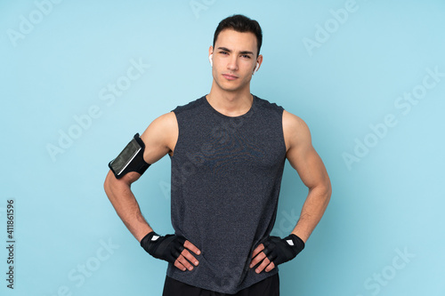 Young sport man over isolated on blue background posing with arms at hip © luismolinero