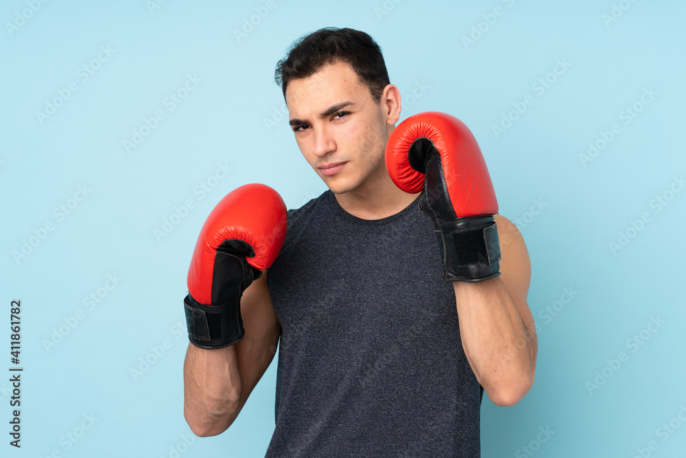 Young sport man over isolated on blue background with boxing gloves Young sport man over isolated on blue background with boxing gloves