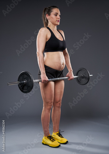 Pregnant lady doing fitness on gray