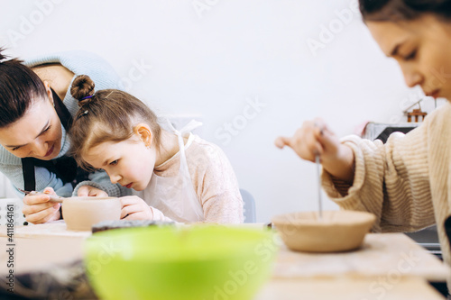 Mother and daughter decorate a clay plate before firing in a pottery studio, decorate a plate with lavender branches