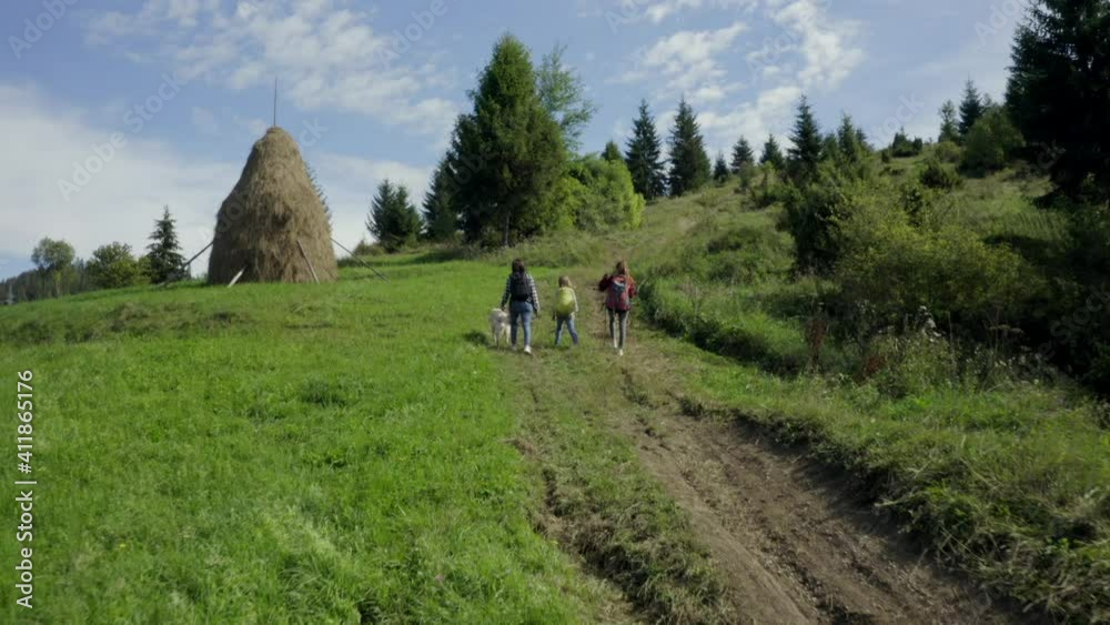 Rear view of family trekking in mountains with golden retriever dog in sunny day Rear view of family trekking in mountains with golden retriever dog in sunny day