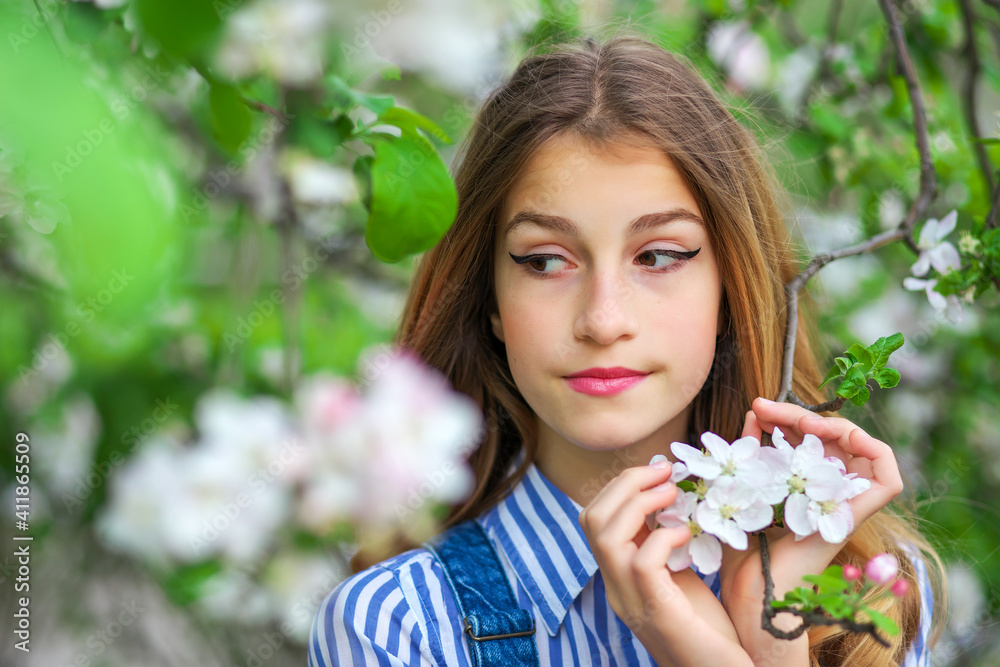 Fototapeta premium Pretty teen girl are posing in garden near blossom tree with white flowers. Spring time