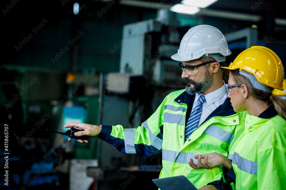 Male and female industrial engineer explaining the workplace. He is holding the walkie talkie on his hand while the pointing. Male and female industrial engineer explaining the workplace. He is holding the walkie talkie on his hand while the pointing.
