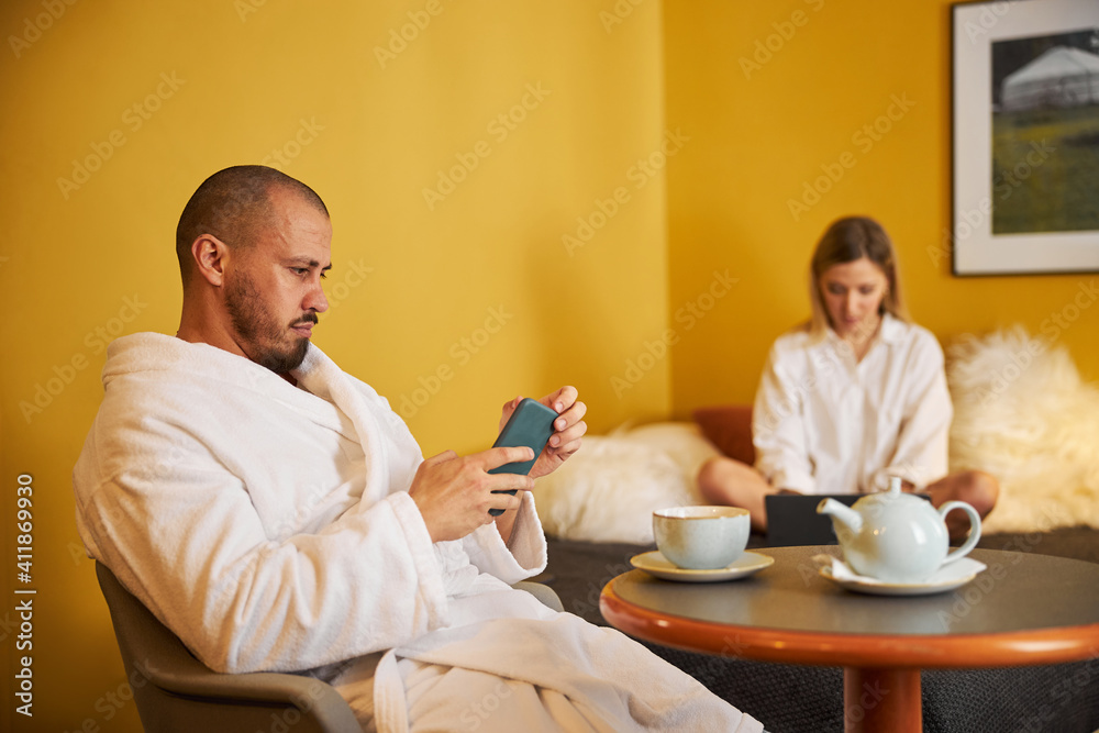 Focused man and his wife using their gadgets Focused man and his wife using their gadgets