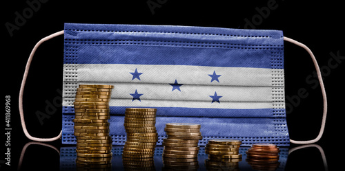 Medical mask with the flag of Honduras behind some shrinking stacks of various coins.(series) photo