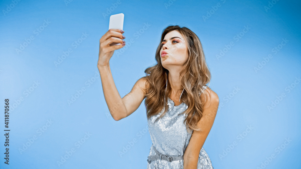 woman blowing kiss while taking selfie on blue woman blowing kiss while taking selfie on blue