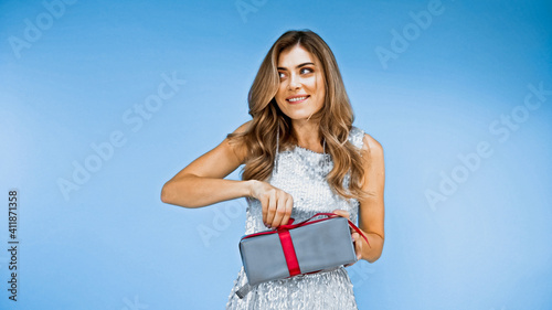 happy woman holding wrapped gift box isolated on blue