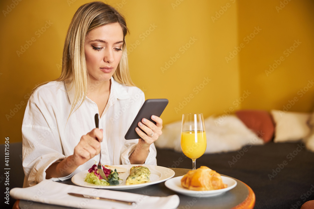 Focused lady reading a text message at breakfast Focused lady reading a text message at breakfast