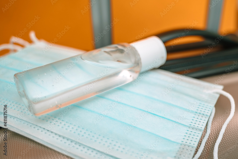 Medical face masks and hand sanitizer are on the travel luggage suitcase. Travel concept during the coronavirus outbreak Medical face masks and hand sanitizer are on the travel luggage suitcase. Travel concept during the coronavirus outbreak