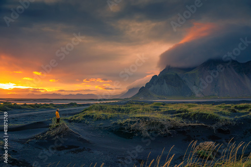Tourist stands on a sand dune at Vestrahorn mountain in Iceland at sunset photo