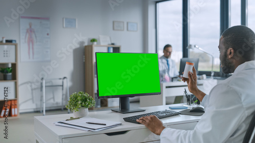 African American Medical Doctor is Making a Video Call with Patient on a Computer with Green Screen Display in a Health Clinic. Assistant in Lab Coat is Talking About Health Issues in Hospital Office. © Gorodenkoff