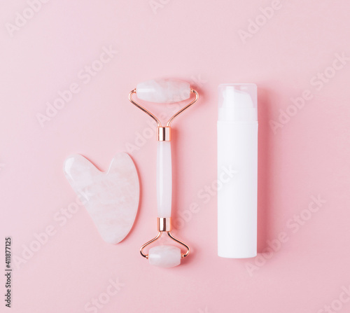 Facial care kit roller massager scraper quartz gua sha cosmetic pink background