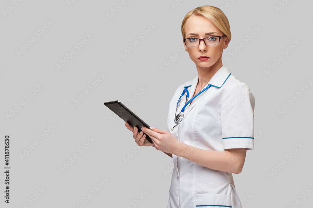beautiful female doctor holding tablet pc pad isolated on grey background beautiful female doctor holding tablet pc pad isolated on grey background