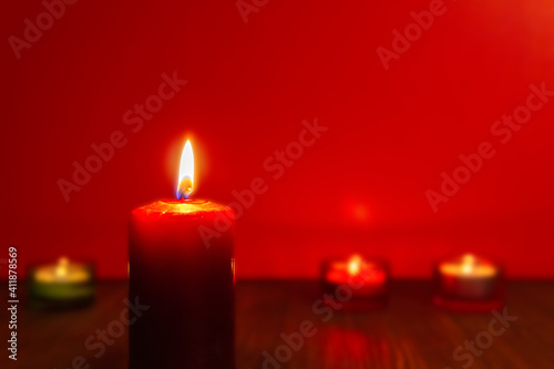 Burning red candle and other candles on red background