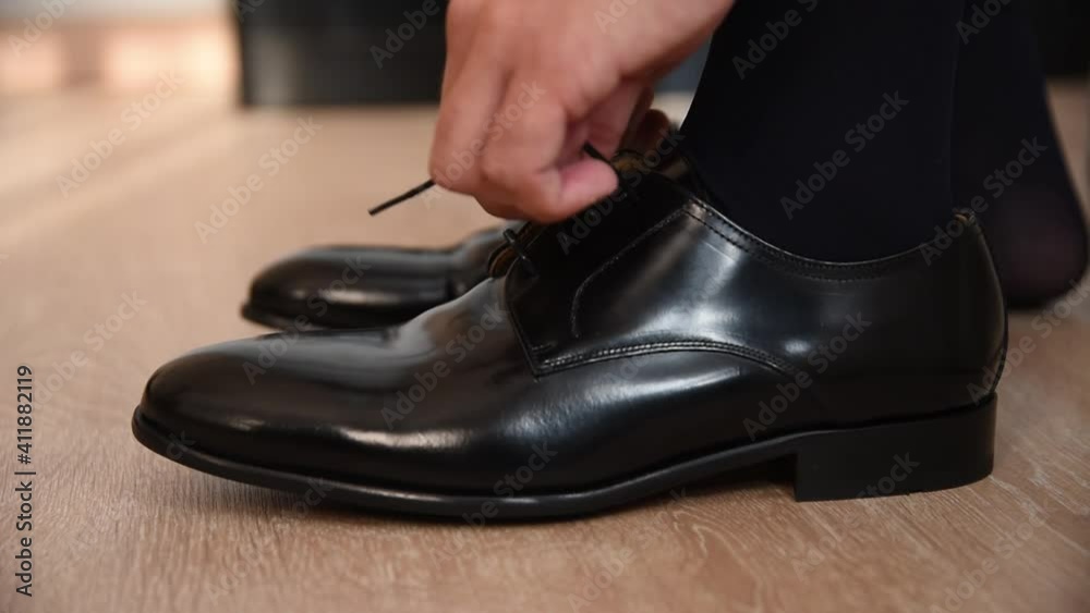A gentleman putting on elegant shoes. A businessman putting on black shoes A gentleman putting on elegant shoes. A businessman putting on black shoes