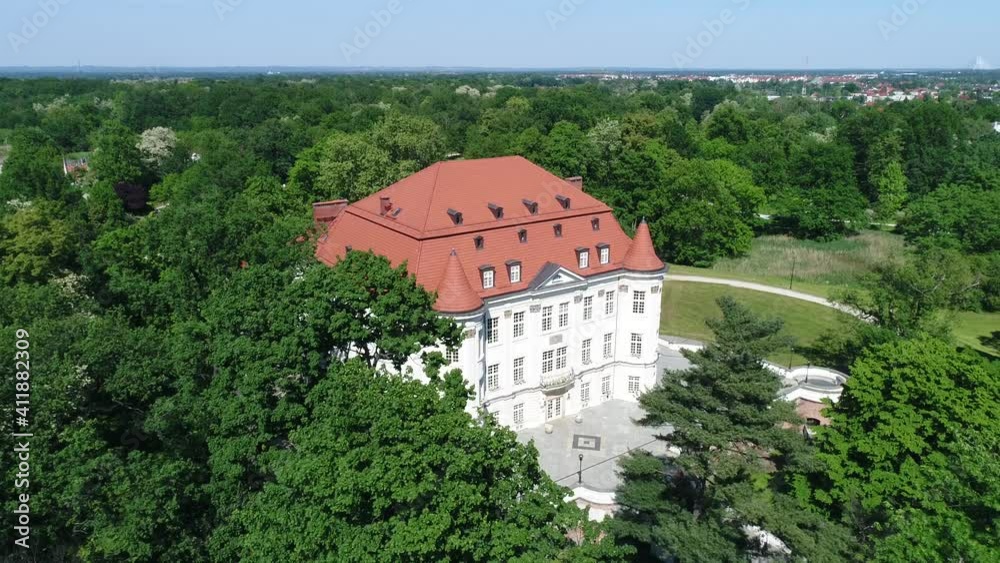 A renovated palace in one of the Polish towns. The white facade contrasts with the greenery of the nearby trees. Sunny day, drone video. A renovated palace in one of the Polish towns. The white facade contrasts with the greenery of the nearby trees. Sunny day, drone video.