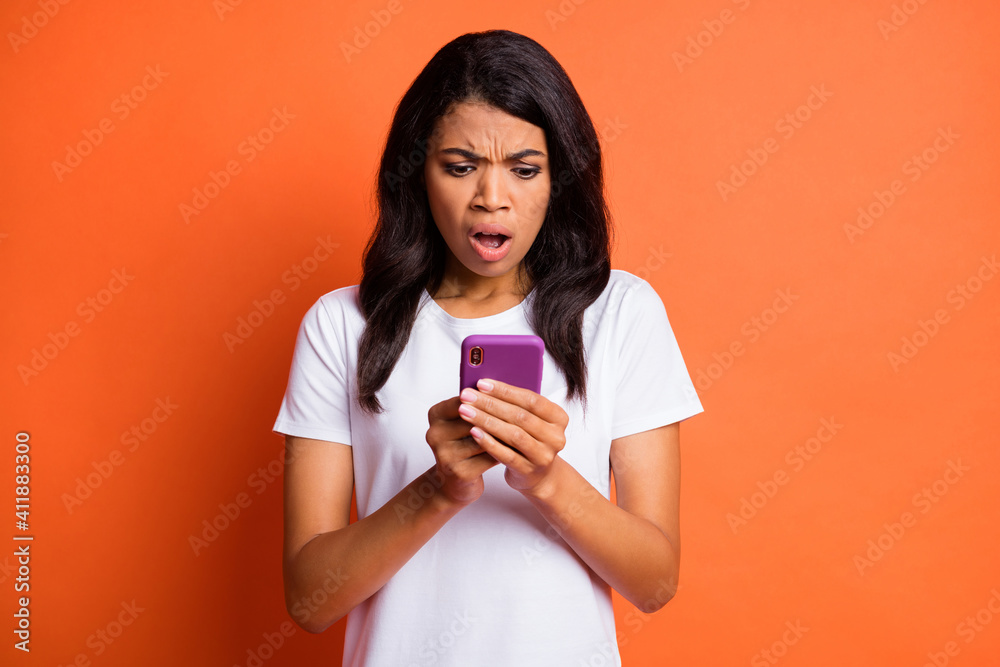 Photo of offended mad lady hold telephone look screen open mouth wear white t-shirt isolated orange color background Photo of offended mad lady hold telephone look screen open mouth wear white t-shirt isolated orange color background