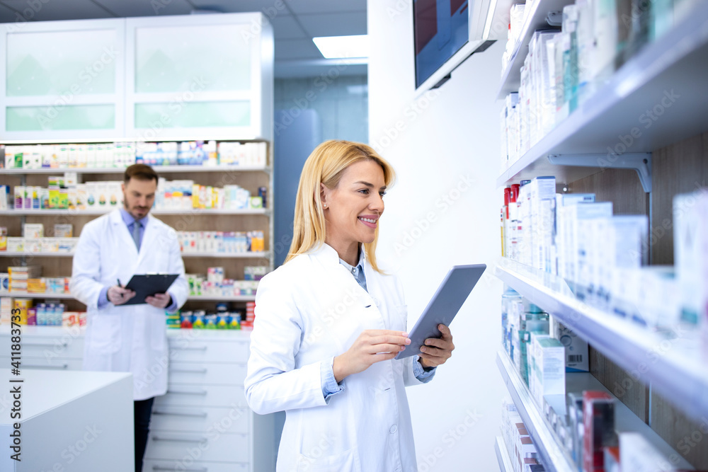 Female blonde pharmacist checking medicine inventory at drugstore. Medicine and healthcare concept.