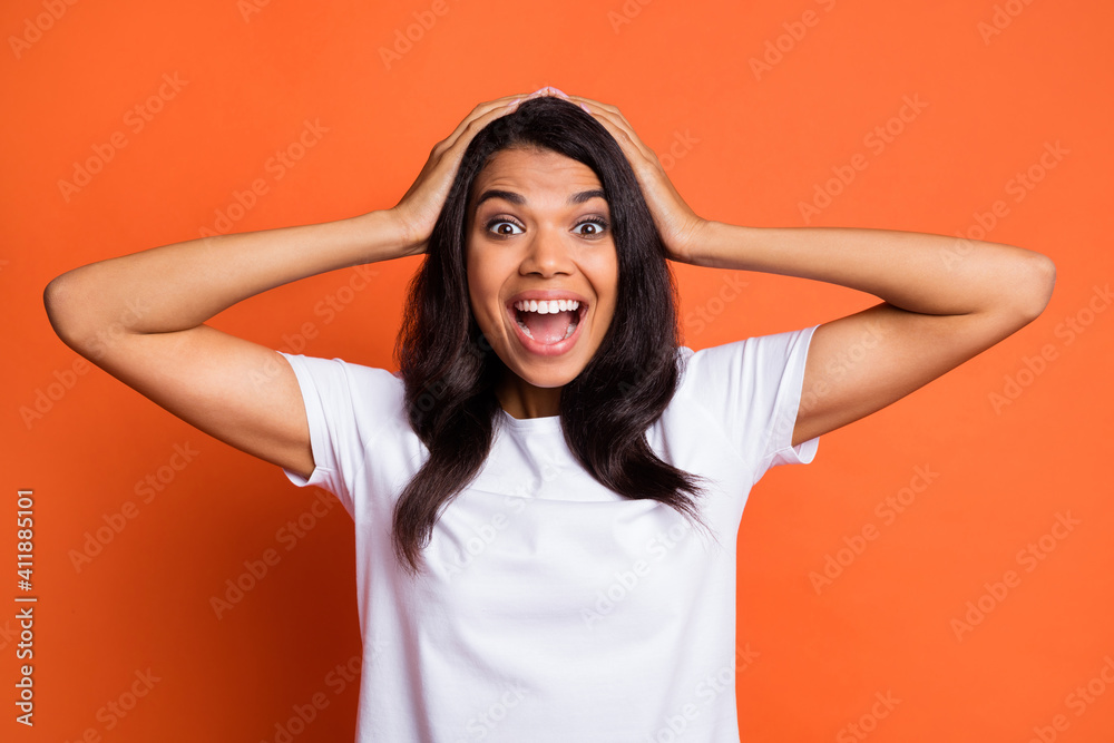 Portrait of impressed girl arms head wear white t-shirt isolated on orange color background Portrait of impressed girl arms head wear white t-shirt isolated on orange color background