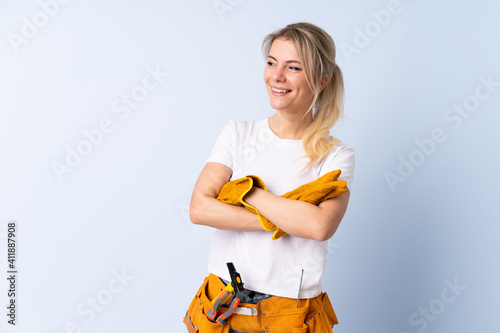 Electrician woman over isolated blue background laughing